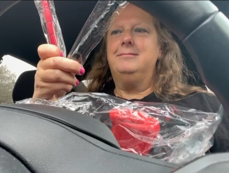 Customer unboxing the From Texas W/❤️ Empowerment Pack inside car, holding red self-defense keychain  and black self-defense keychain and GRUPS trainer.